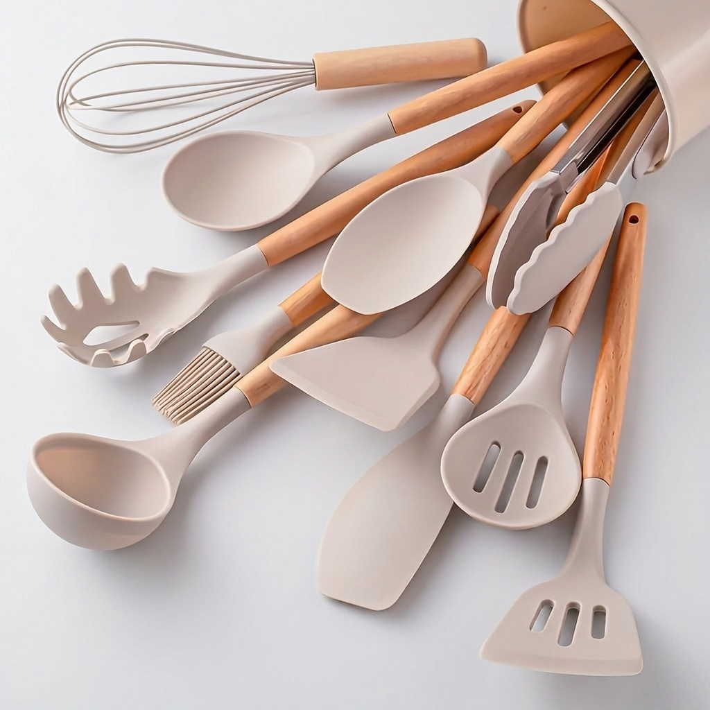 A set of kitchen utensils with matte beige silicone heads and light natural wood handles, arranged in a white container on a clean white background.