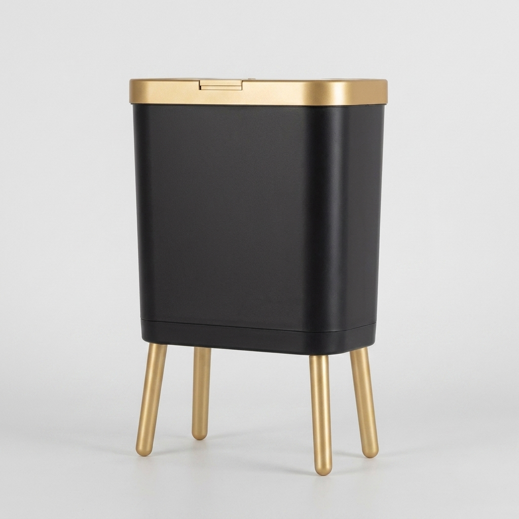 A modern black rectangular trash can with a brushed gold lid and four gold legs, shown on a light gray background.
