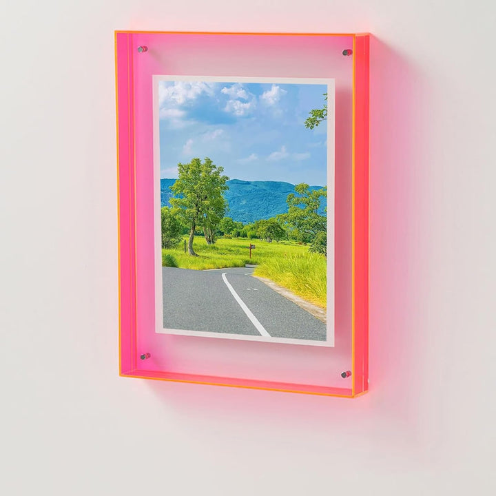 Framed photograph of a scenic road with trees and blue sky, mounted on a white wall.