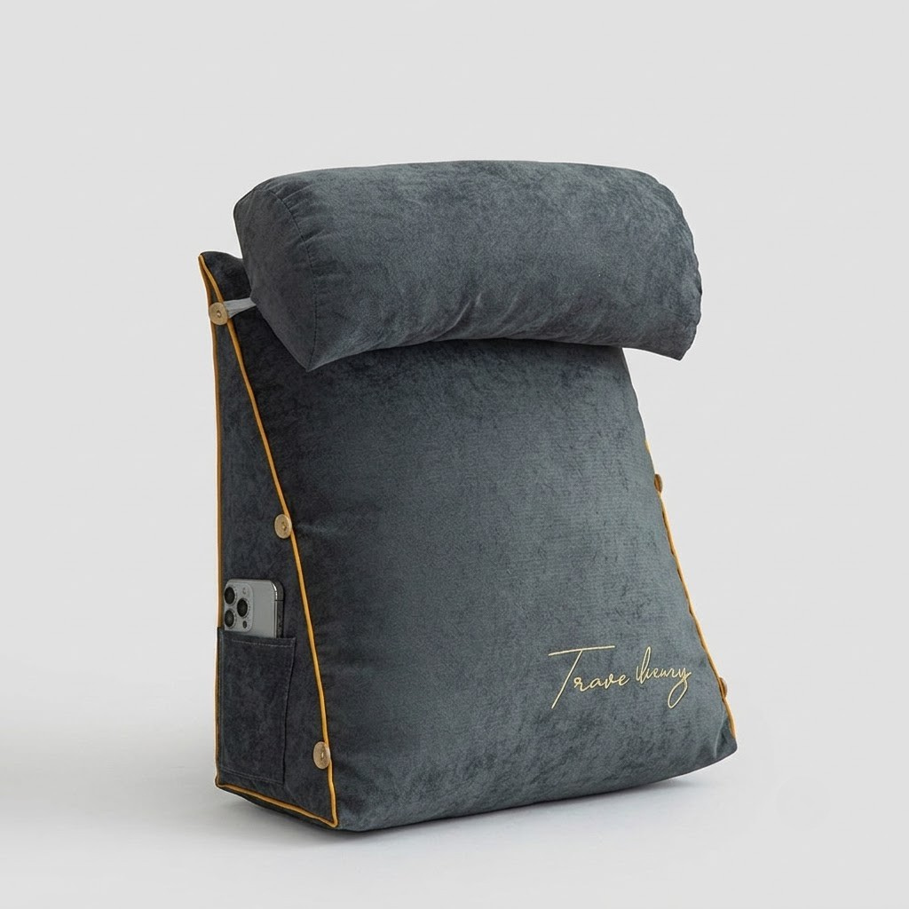 A dark gray travel pillow with a matching headrest, featuring gold piping, a side pocket holding a smartphone, and gold script embroidery on the front, set against a light gray background.