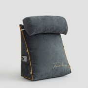 A dark gray travel pillow with a matching headrest, featuring gold piping, a side pocket holding a smartphone, and gold script embroidery on the front, set against a light gray background.