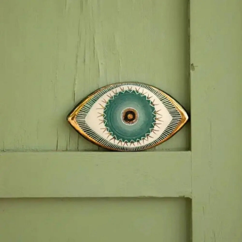 Decorative wall art piece resembling an eye on a green wooden background