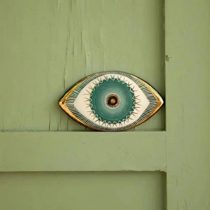 Decorative wall art piece resembling an eye on a green wooden background