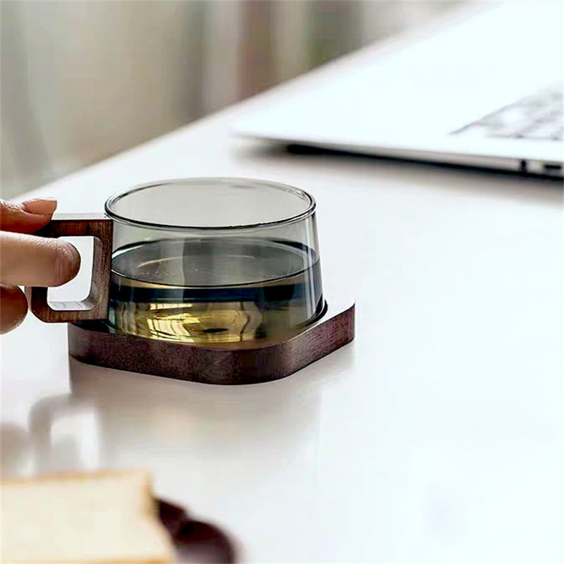 Glass mug with wooden handle and base on a white surface