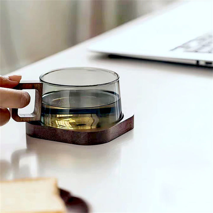 Glass mug with wooden handle and base on a white surface