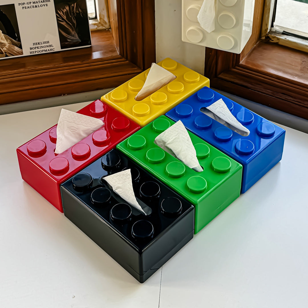 Colorful block-shaped tissue box with tissues on a surface.