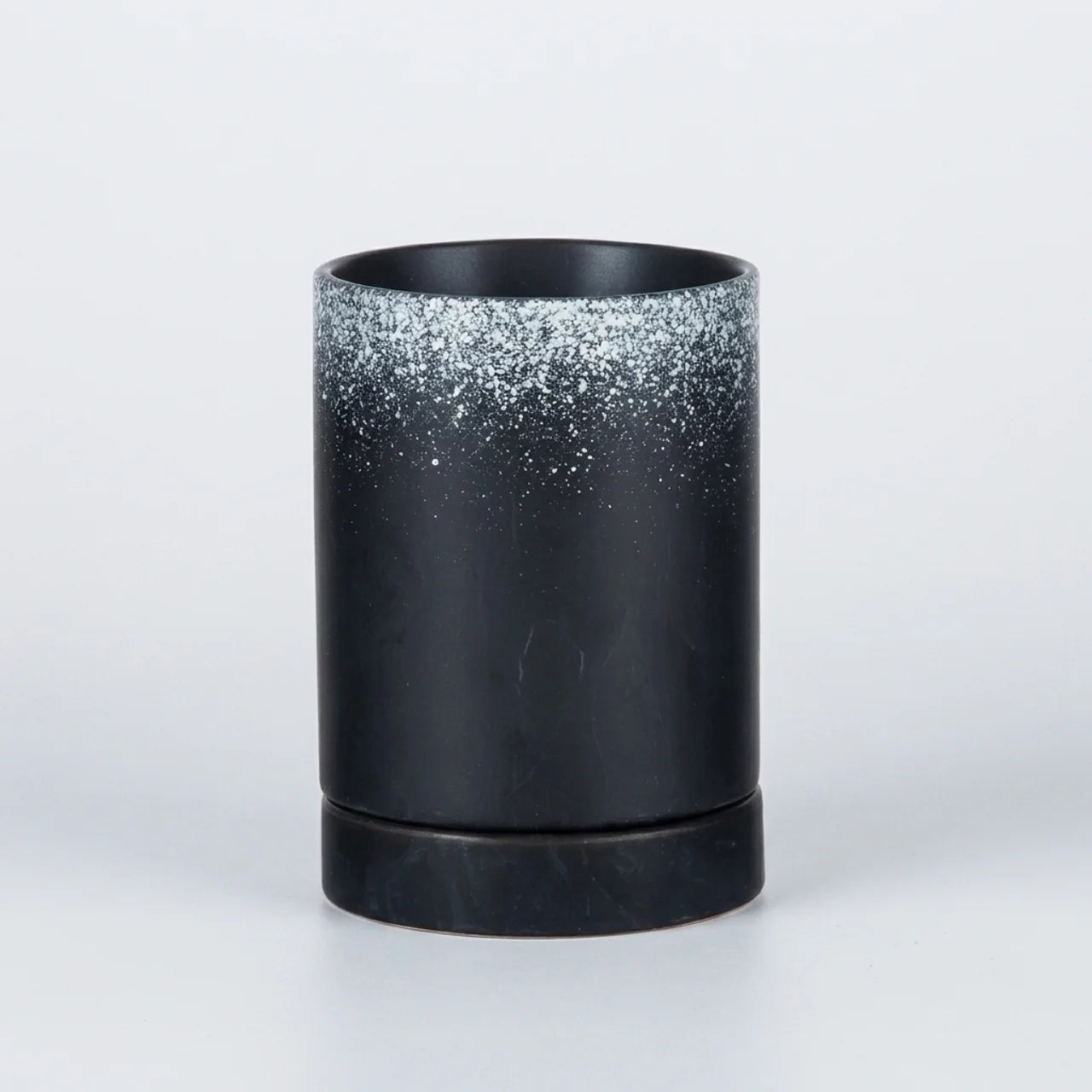 A black cylindrical candle holder or vase with a textured, glittery silver gradient near the rim, set against a clean white background.
