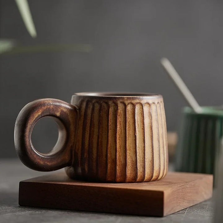 Brown ceramic mug with ribbed texture on a wooden coaster against a dark background