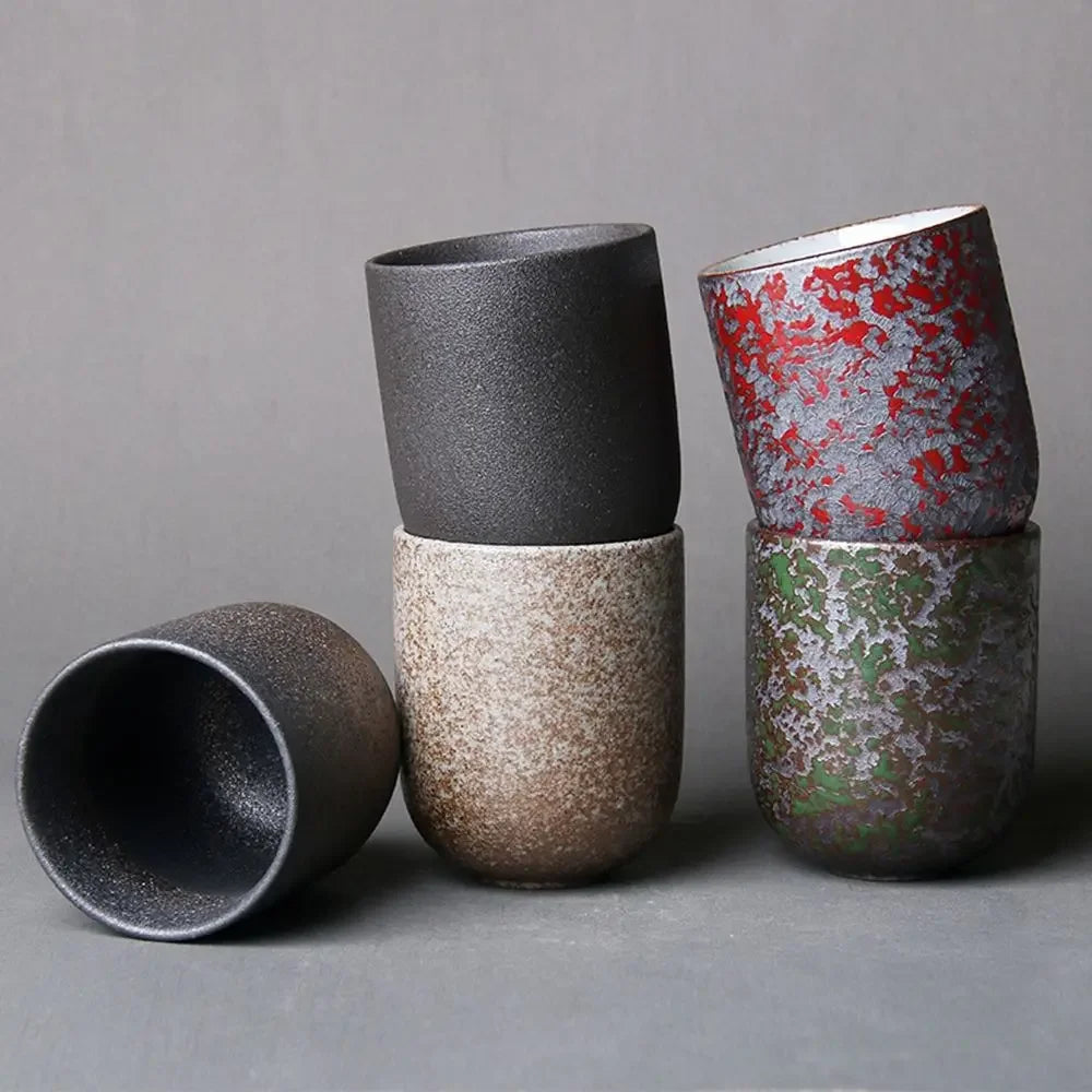 Set of four ceramic cups with textured surfaces on a gray background