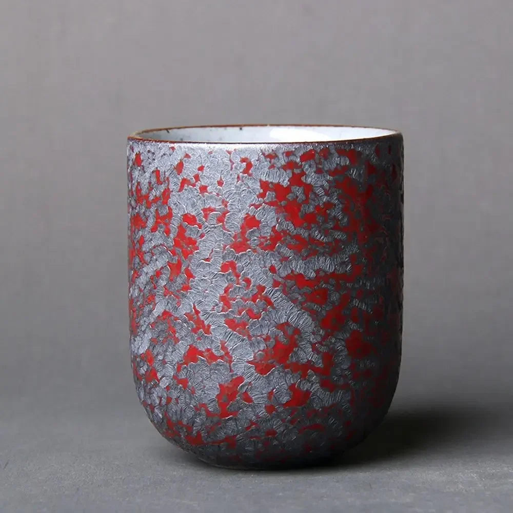 Ceramic cup with red and silver pattern on a gray background