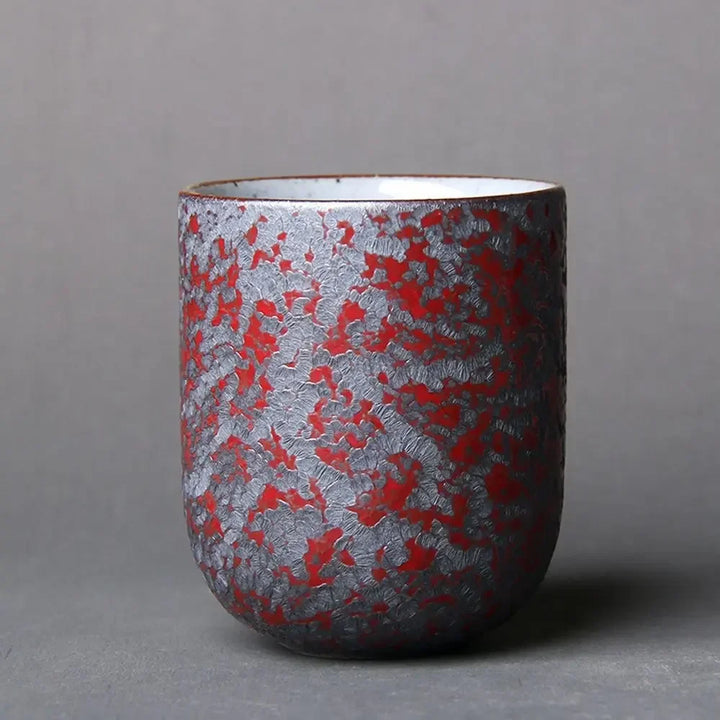 Ceramic cup with red and silver pattern on a gray background