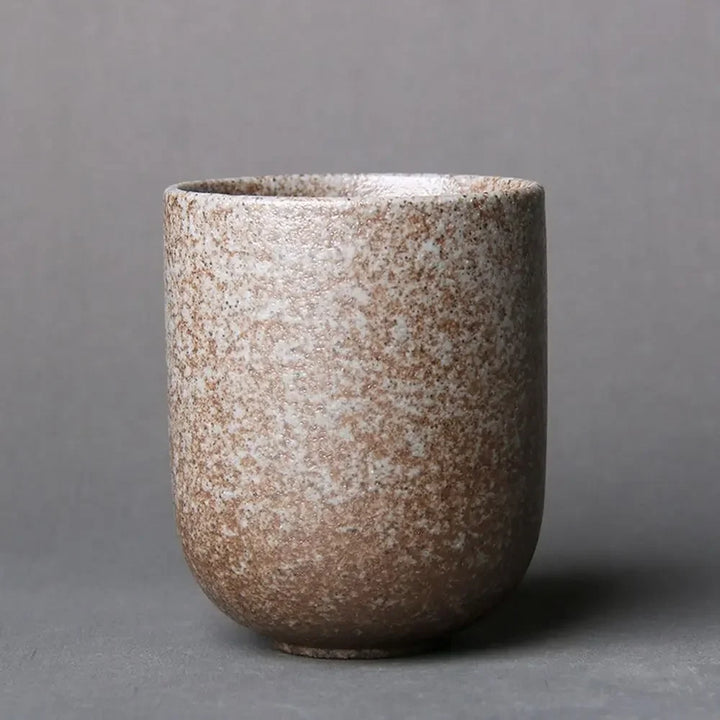 Speckled brown ceramic cup on a gray background