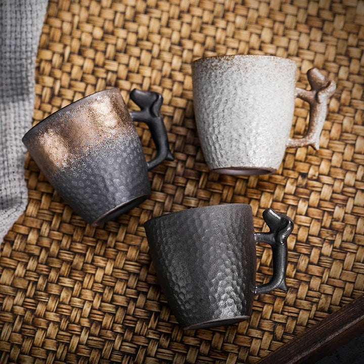 Three ceramic mugs with textured surfaces on a woven mat