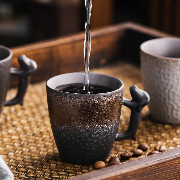 Hot water being poured into a dark ceramic mug on a woven mat with coffee beans.