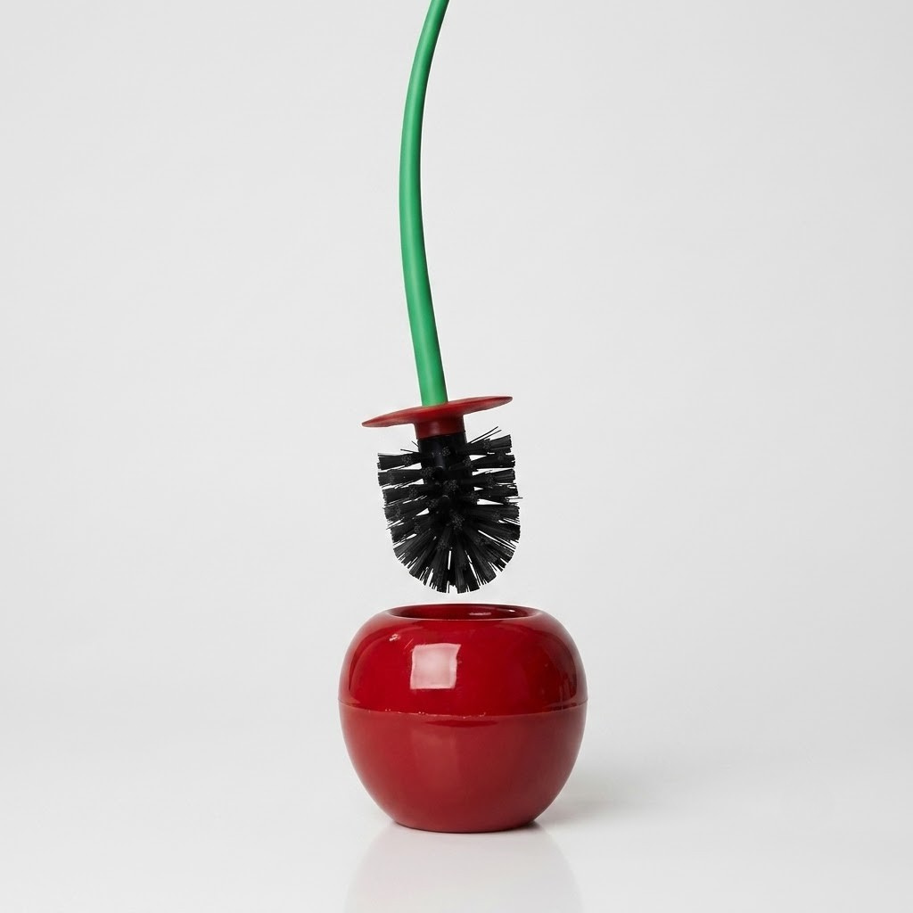 A glossy red apple-shaped toilet brush holder with a green-handled toilet brush inserted, photographed on a clean white studio background.