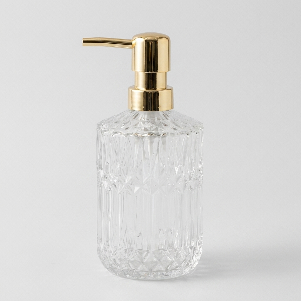 A clear faceted glass bottle with a polished gold pump dispenser, shown on a light gray background.
