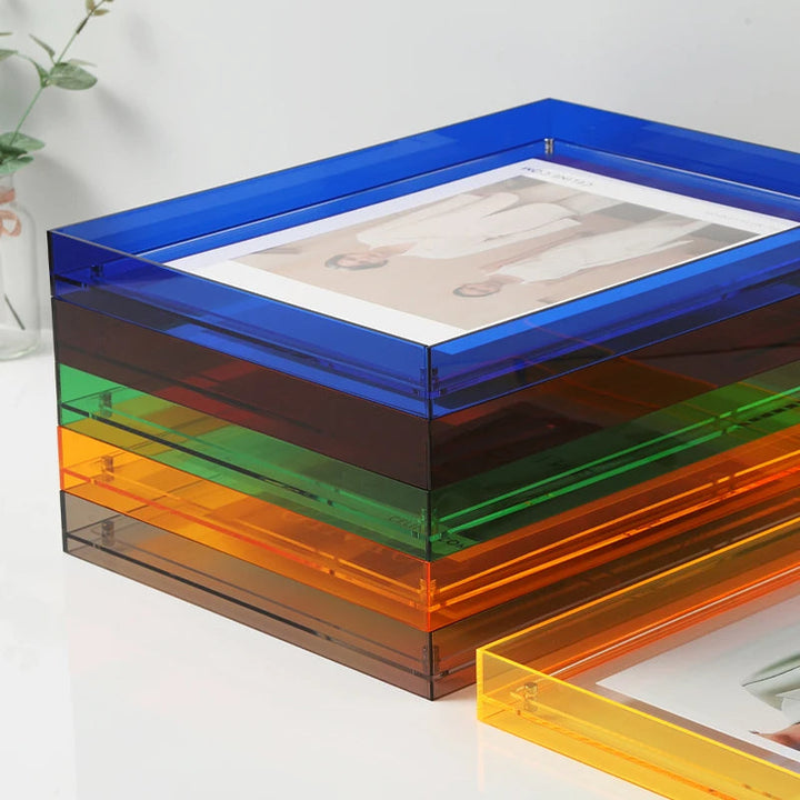 Colorful transparent acrylic photo frame on a white surface with a plant in the background.