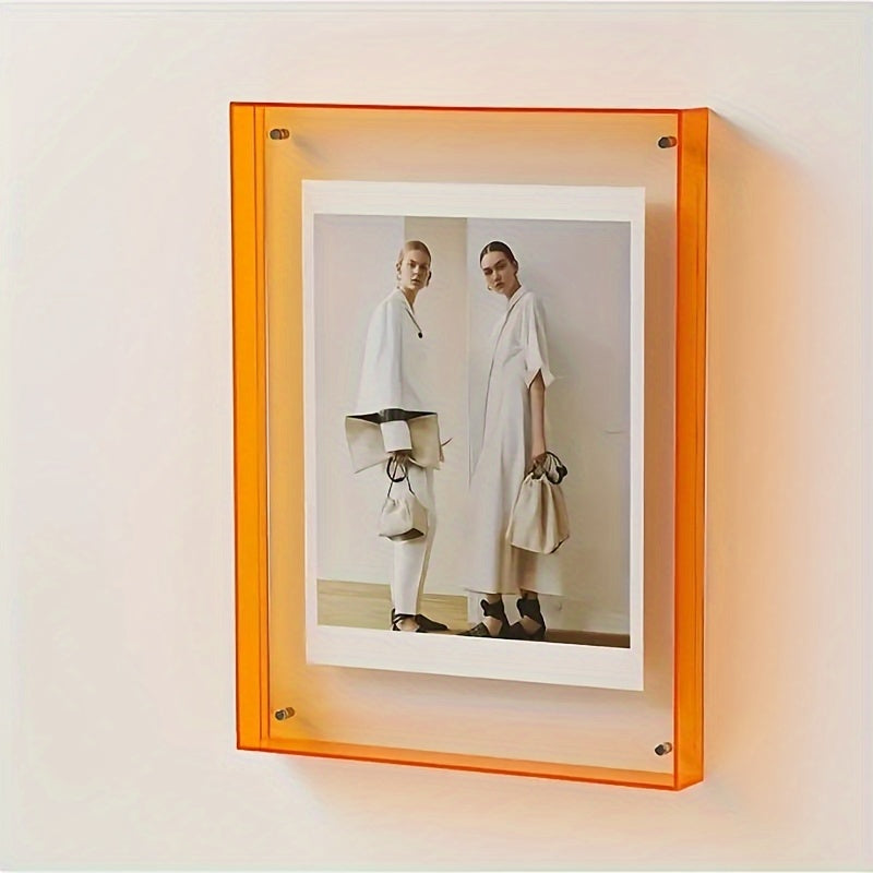 Framed photograph of two people holding bags inside an orange frame on a light beige wall.