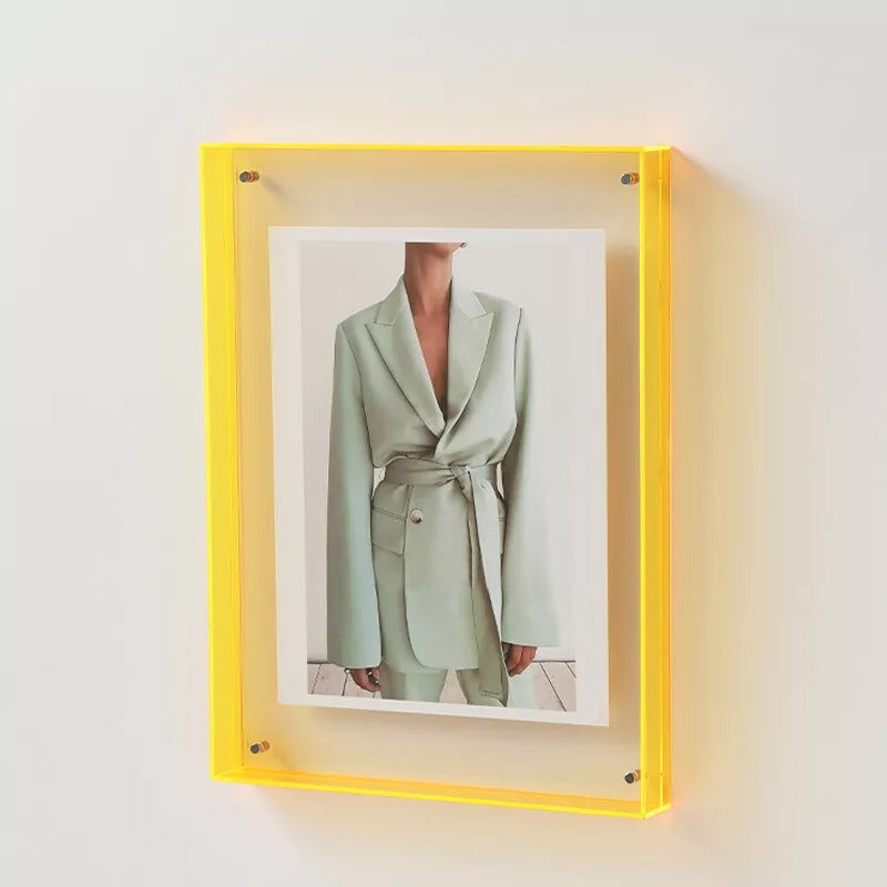 Yellow-framed photograph of a person wearing a light green suit against a white background