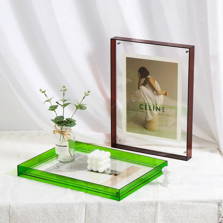 Green acrylic tray with a framed picture and small plant on a white surface