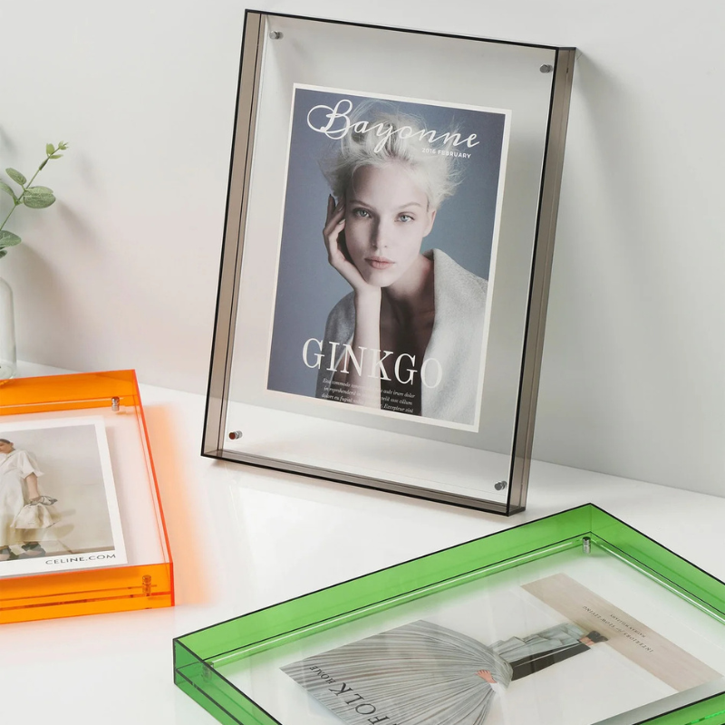 Three framed pictures on a white surface with a magazine cover in a silver frame.