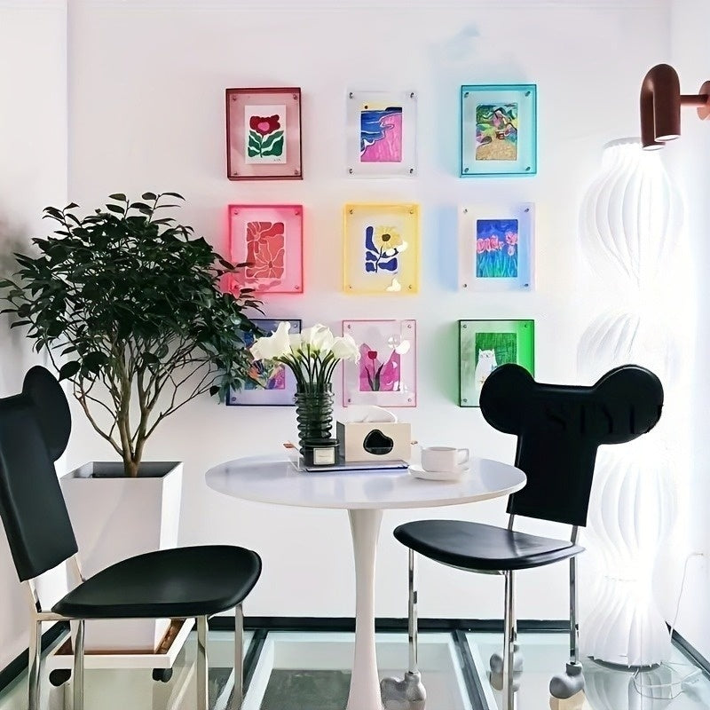 Modern interior with a round white table and black chairs, colorful wall art, and a plant.