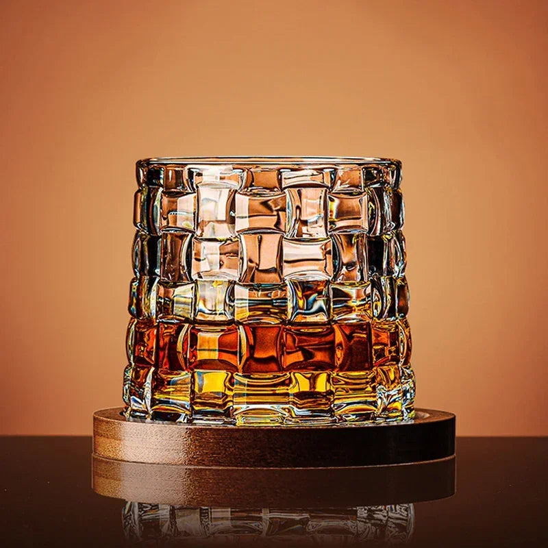 Glass with a textured pattern filled with a amber liquid on a reflective surface with a warm brown background