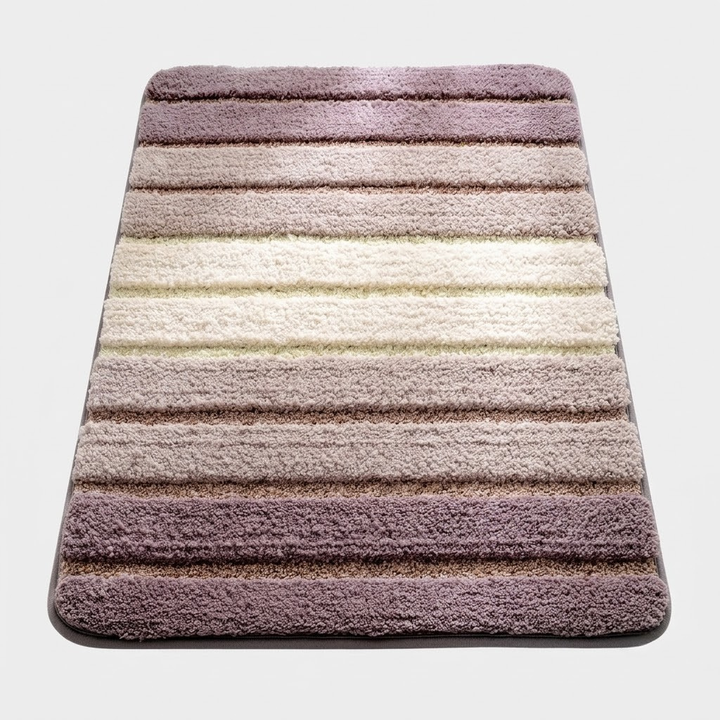 A rectangular plush bath mat with rounded corners, featuring horizontal stripes in shades of mauve, dusty rose, beige, and cream, shown from a top-down perspective on a light gray background.