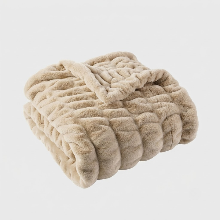 A folded plush chenille blanket in a light beige color, shown against a plain light gray background.