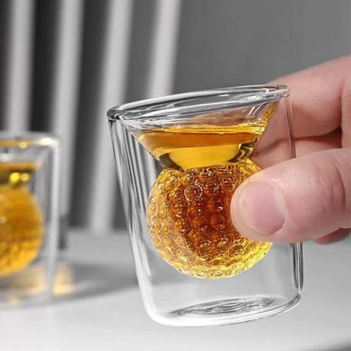Hand holding a double-walled glass with honeycomb design filled with amber liquid.