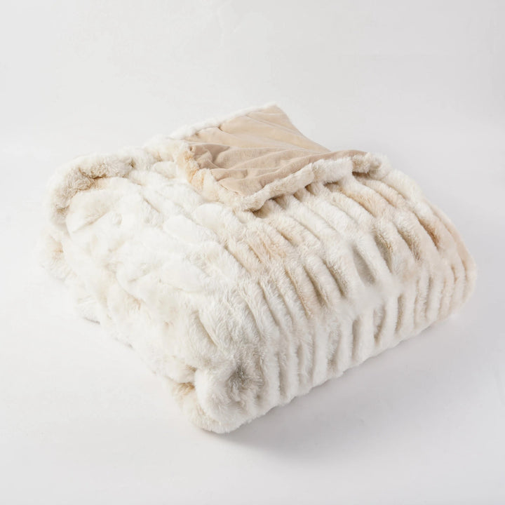 Folded beige and white textured blanket on a light gray background