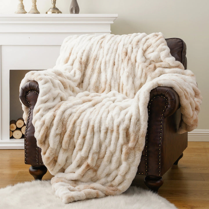 Cozy beige blanket draped over a brown armchair in a home setting.