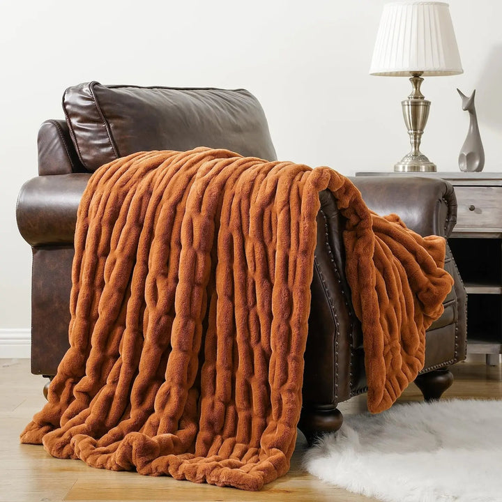 Brown textured blanket draped over a brown leather armchair in a living room setting.