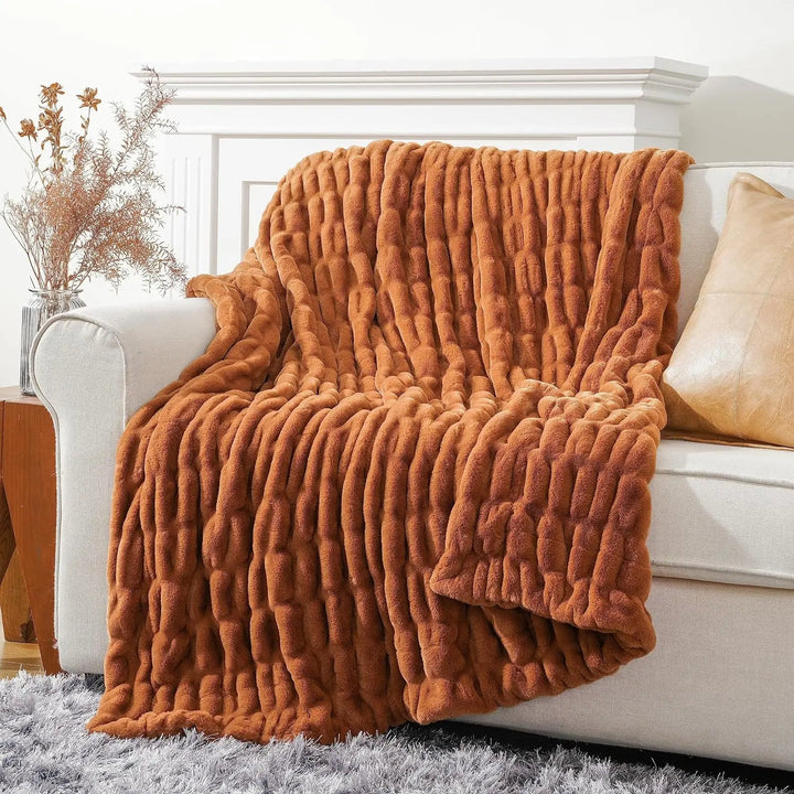 Brown textured blanket draped over a white sofa in a living room setting.