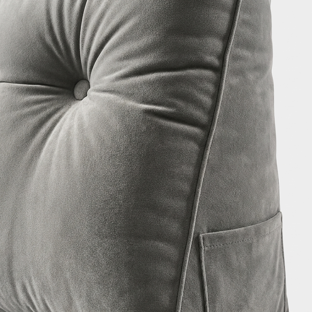 Close-up of a gray tufted velvet cushion with a buttoned center and a side pocket, shown against a light gray background.