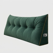 A dark green tufted wedge floor cushion with a side pocket holding a smartphone, shown on a light gray background.