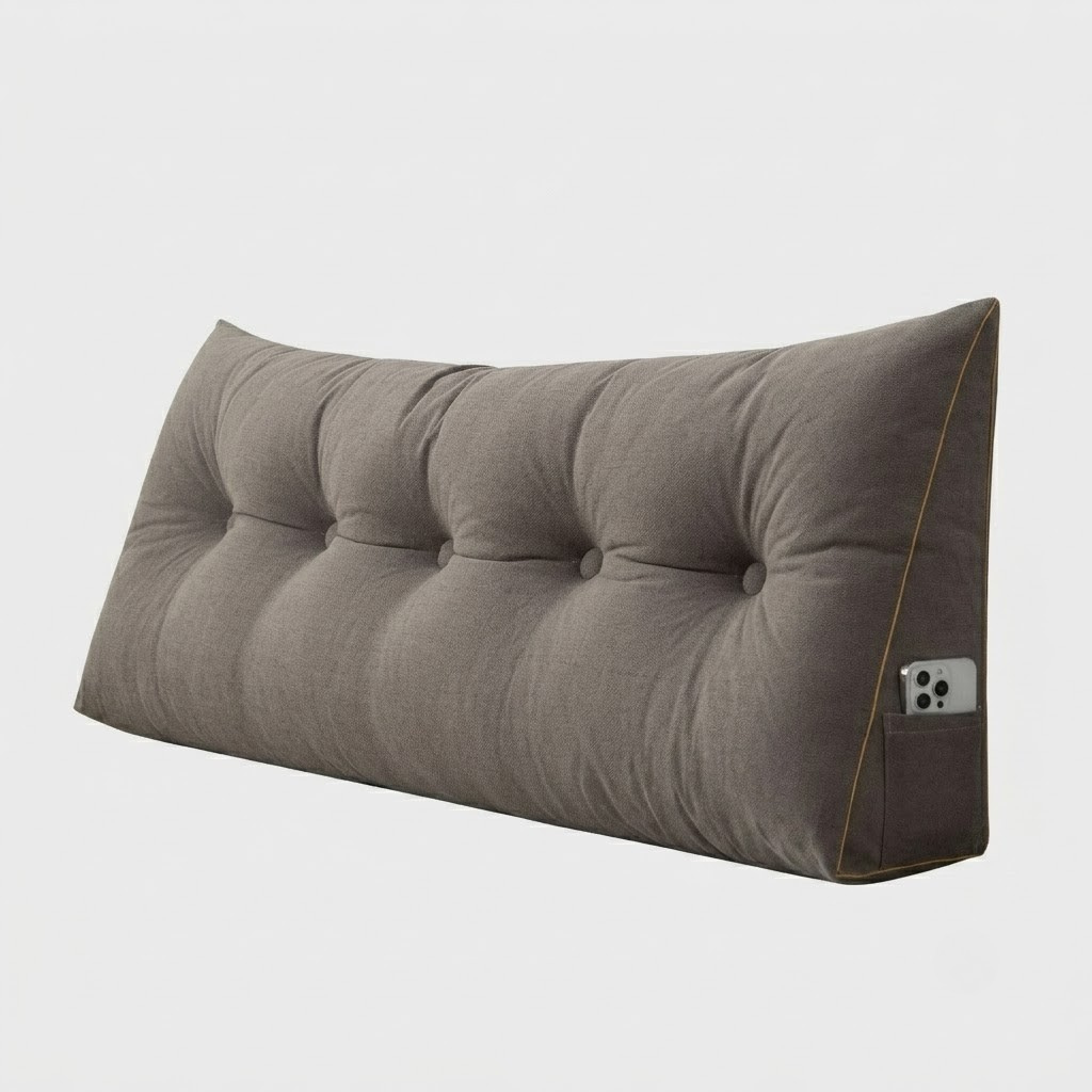 A long, tufted wedge floor cushion in a taupe-gray fabric, shown at an angle on a light gray background. A silver smartphone is tucked into a side pocket on the right edge.