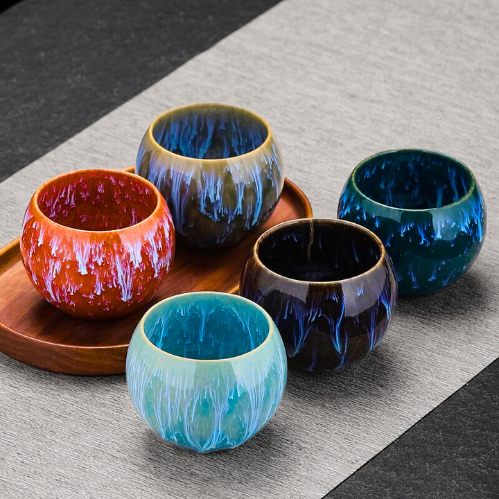 Set of colorful ceramic cups on a wooden tray with a gray surface background