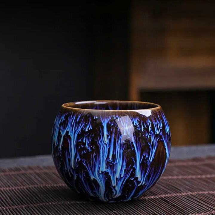 Ceramic cup with blue and black glaze on a dark background