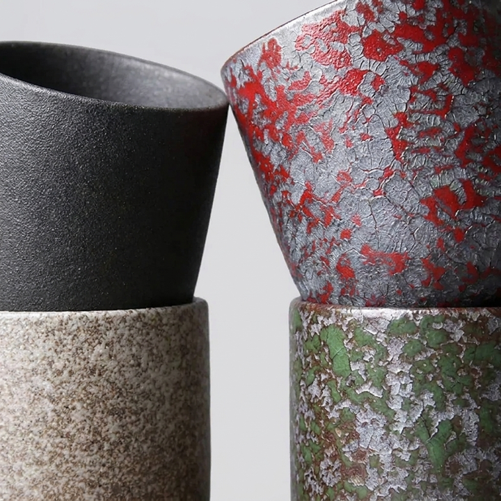 Three stacked ceramic planters with textured, distressed finishes in black, speckled beige, red-splattered silver, and green-splattered silver.