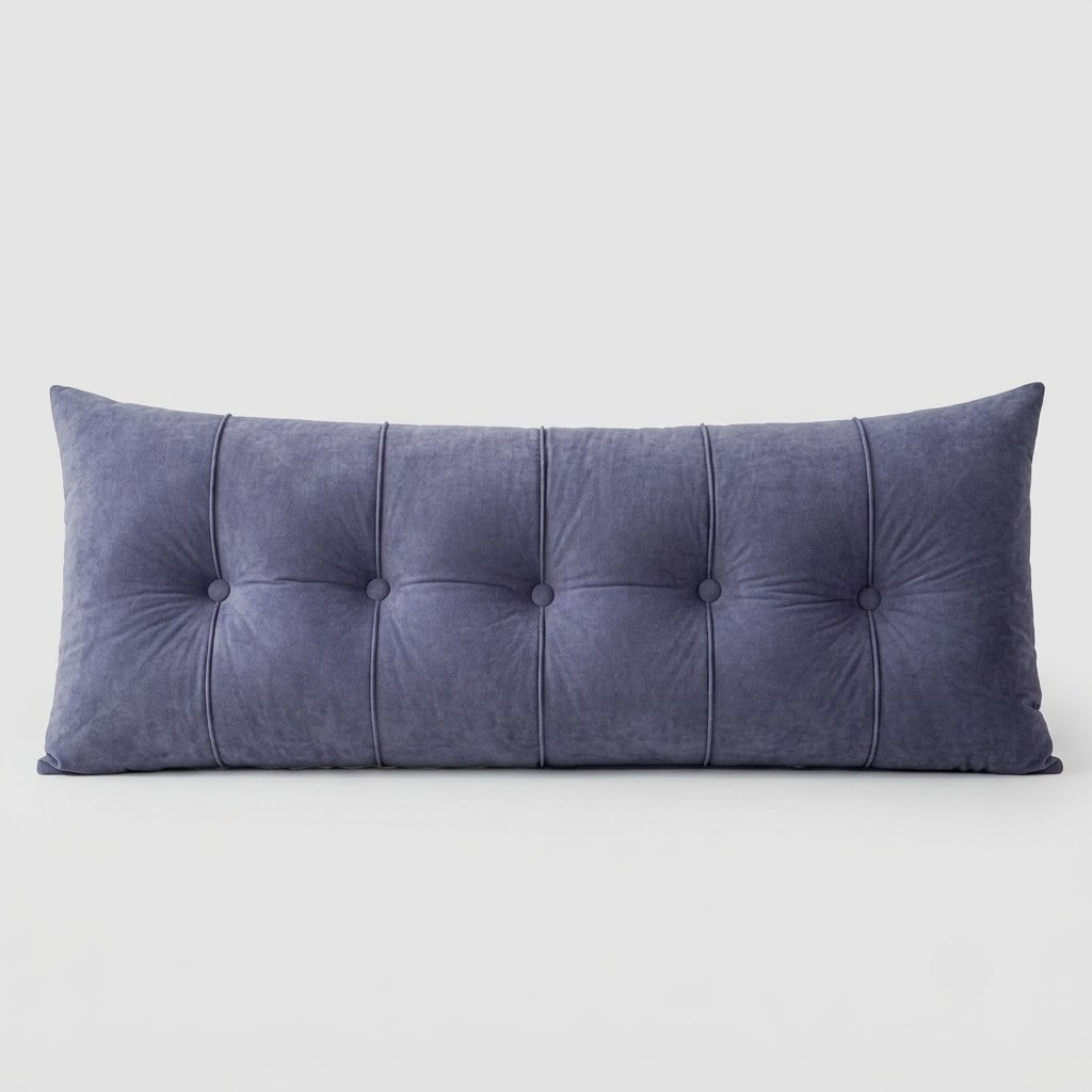 A long rectangular lumbar pillow in a textured slate blue velvet fabric, featuring vertical channel tufting with button details, shown against a neutral light gray background.