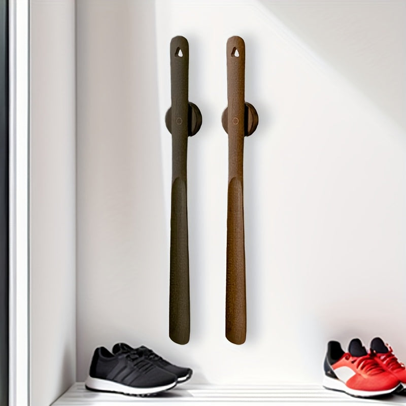 Two wooden shoe trees on a white surface with shoes at the base.
