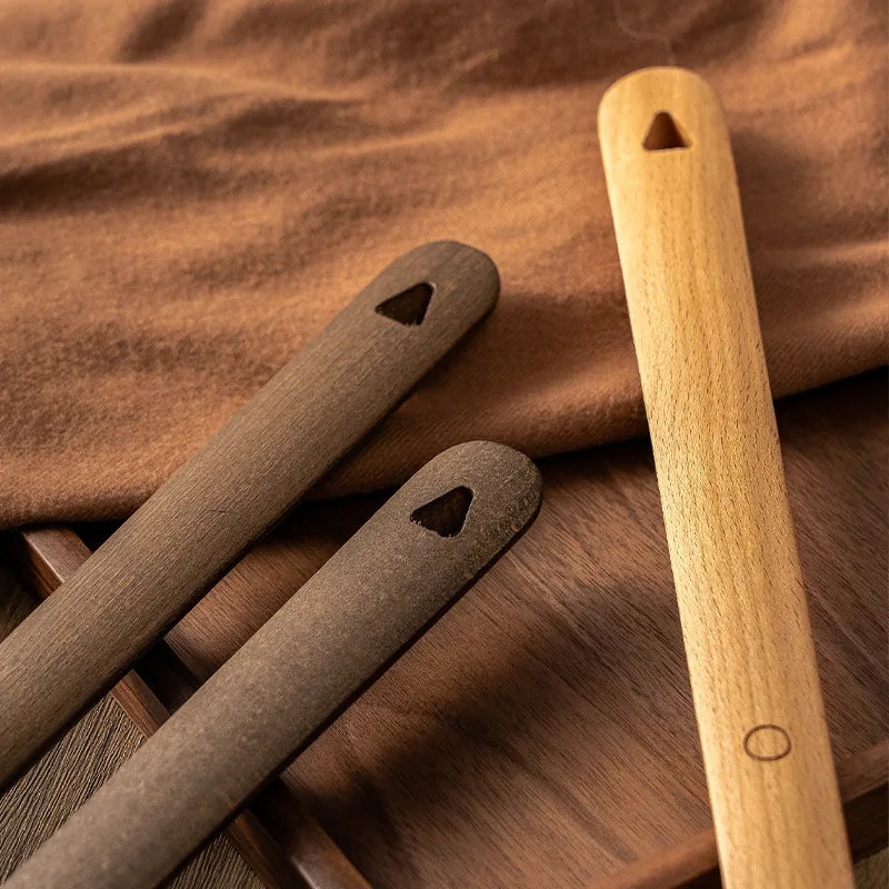 Three wooden tools with holes on a wooden surface