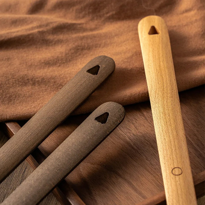 Three wooden tools with holes on a wooden surface