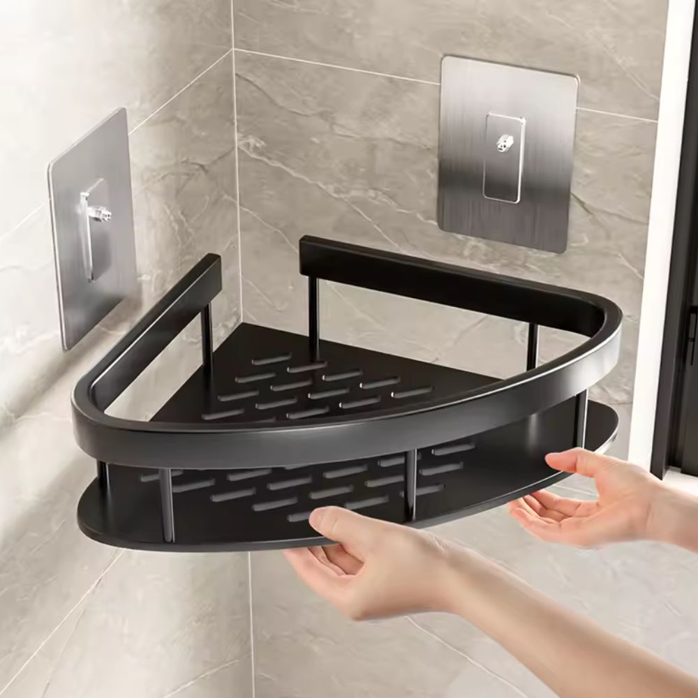 Black corner shower caddy being held against a tiled bathroom wall.