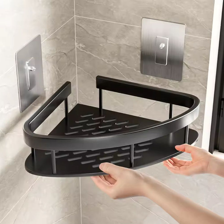 Black corner shower caddy being held against a tiled bathroom wall.