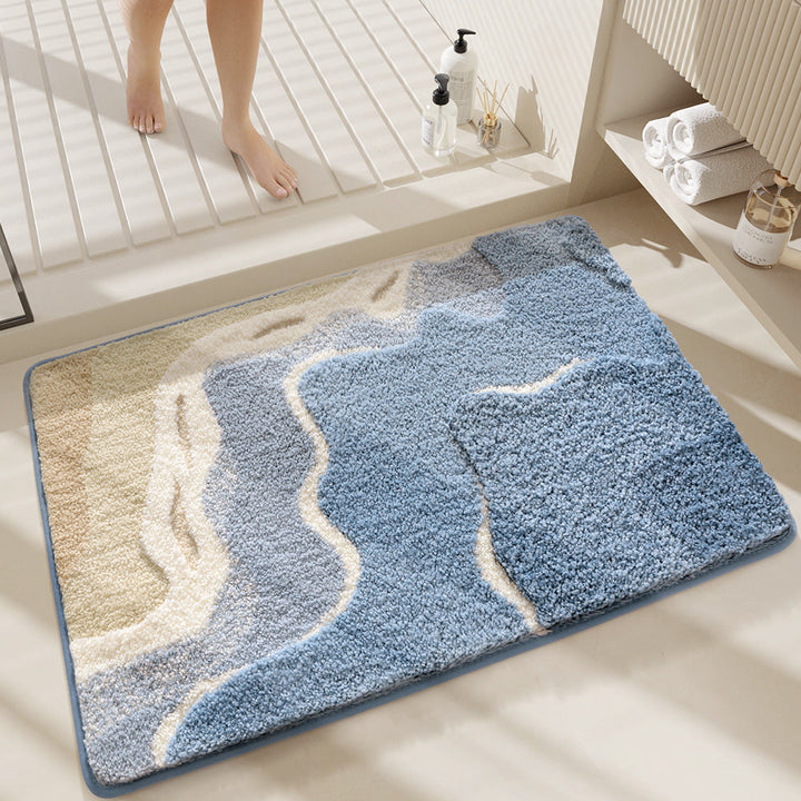 Blue and beige bath mat on a bathroom floor with a person's feet in the background.