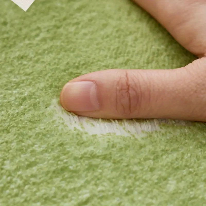 Close-up of a finger pressing on green textured paper