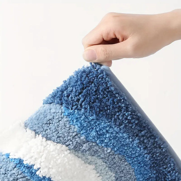 Hand lifting a blue and white textured rug to show its thickness.