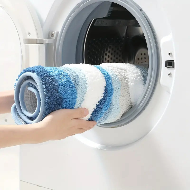 Person placing a blue and white striped rug into a washing machine.